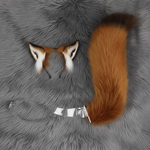 Puede incluir: Un conjunto de disfraz de zorro con una cola esponjosa, naranja y marrón, y un par de orejas de zorro a juego en una diadema. Las orejas tienen detalles en blanco y negro. También se incluye un cinturón de plástico transparente.