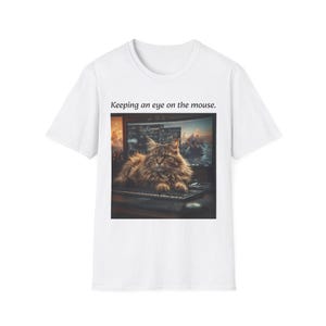 May include: White t-shirt featuring a fluffy brown cat lying on a keyboard in front of a computer screen. The text "Keeping an eye on the mouse" is printed above the image. The cat has long fur and is looking at the screen.