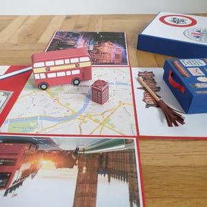 Könnte beinhalten: Ein handgefertigtes London-Themen-Bastelset. Es enthält einen roten Doppeldeckerbus, eine rote Telefonzelle und eine blaue Box mit rotem Griff. Das Set enthält auch Bilder von Big Ben und eine Londoner Karte.
