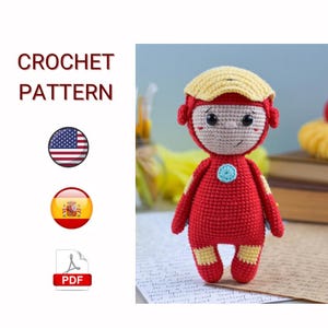 Puede incluir: Muñeca de ganchillo roja y amarilla hecha a mano, que se asemeja a un superhéroe, con un emblema de pecho azul claro. La muñeca tiene un casco amarillo. El texto "CROCHET PATTERN" está incluido.