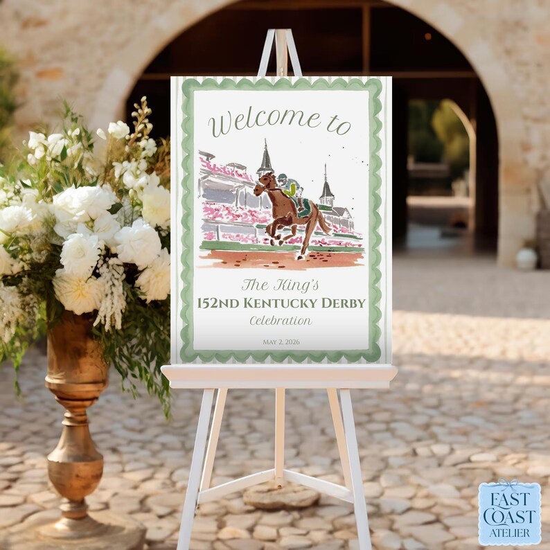 May include: A white easel displays a sign with a watercolor illustration of a horse race. The sign reads "Welcome to The King's 152nd Kentucky Derby Celebration" with the date "May 2, 2026". The sign has a green scalloped border.