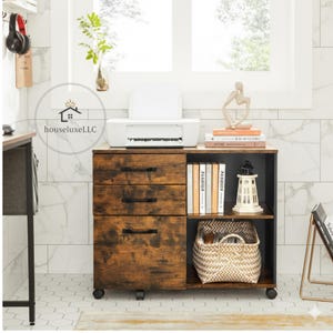 May include: A rustic brown wooden file cabinet with three drawers and a shelf. The cabinet has black hardware and sits on wheels. A white printer, books, and decorative items are on top. A woven basket and a lighthouse decoration are on the shelf.