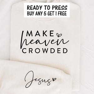 May include: Cream-colored sweatshirt with the text "MAKE heaven CROWDED" in black script. The sleeve displays the word "Jesus" in a similar script. A white rectangle at the top reads "READY TO PRESS BUY ANY 5 GET 1 FREE".