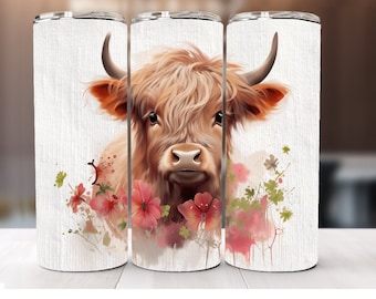 May include: A white tumbler with a watercolor design of a Highland cow with pink flowers. The cow has a brown and white coat and is looking directly at the viewer.