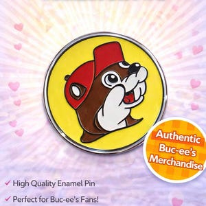 May include: A circular enamel pin with the Buc-ee's beaver mascot in a red hat on a yellow background. The pin has a silver edge and the text "BUC-EE'S COLLECTOR PIN!" and "Authentic Buc-ee's Merchandise" is displayed.