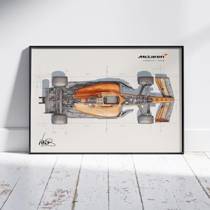 May include: A framed print featuring a top-down schematic of a McLaren Formula 1 race car. The car is rendered in orange and gray tones, with detailed mechanical components visible. The McLaren logo is in the upper right corner.