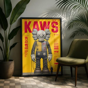 May include: A framed poster with a yellow background and the word "KAWS" in large red letters. The poster features a cartoon figure with a skull-like face and grey ears. The figure is wearing a yellow and grey outfit. The poster is displayed next to a green chair and a potted plant.