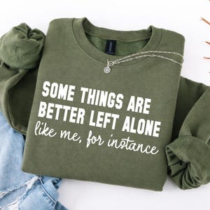 Puede incluir: Una taza de cerámica blanca con un asa negra y el texto "But First, Coffee" en un estilo manuscrito. La taza está sobre una superficie blanca. La taza mide aproximadamente 10 cm de alto.