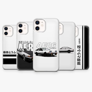 Könnte beinhalten: Eine Sammlung weißer Handyhüllen mit einem schwarz-weißen Autodesign. Die Hüllen zeigen den Text "AE86 TRUENO" und japanischen Text. Das Autodesign ist eine stilisierte Illustration eines klassischen Sportwagens.