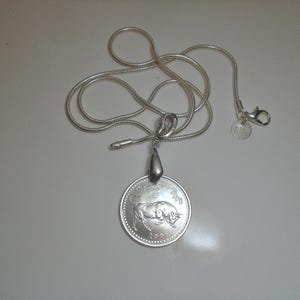 May include: A silver-colored snake chain necklace featuring a round pendant with a bull illustration, the text TAURUS, and the year 2008. The pendant is attached to a silver bail, and the chain includes a lobster clasp with a small round 925 tag.