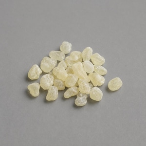 Könnte beinhalten: Eine Ansammlung kleiner, durchscheinender, blassgelber Harztränen oder Gummi-Arabicum-Stücke. Jedes Stück hat eine unregelmäßige, abgerundete Form mit einer leicht texturierten, kristallinen Oberfläche, die in einem Haufen liegt.