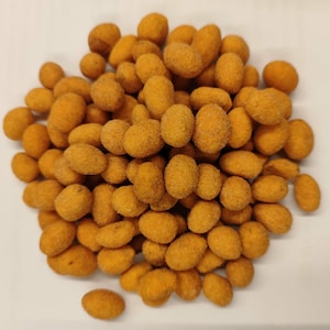 Peut inclure: Gros plan sur un tas de cacahuètes enrobées. Les cacahuètes ont une couleur orange doré et une forme ovale. La surface texturée des cacahuètes est visible. L'image montre une collation.