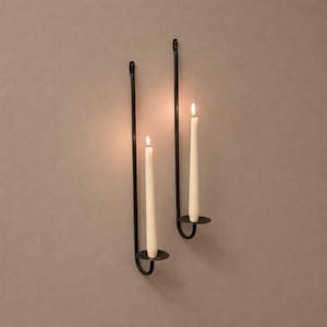 Peut inclure: Deux appliques murales en métal noir, chacune contenant une bougie conique blanche allumée. Les appliques ont un design simple avec une base circulaire. Les bougies diffusent une lueur chaleureuse.