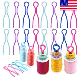 May include: A collection of colorful loop turners in blue, purple, pink, and light blue, arranged with spools of thread in various colors. The image also includes small bottles and an American flag.