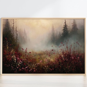 May include: A framed landscape art print featuring a misty forest scene. The artwork depicts a field of red and pink wildflowers in the foreground, with tall, dark trees and a hazy, golden sky in the background. The frame is a light wood color.