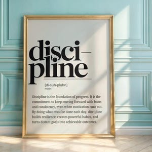 May include: A framed print with the word "discipline" in large, bold, black letters. The definition of discipline is printed below in smaller black text. The frame is gold, and the background is white.