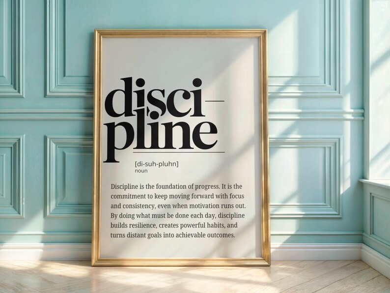 May include: A framed print with the word "discipline" in large, bold, black letters. The definition of discipline is printed below in smaller black text. The frame is gold, and the background is white.