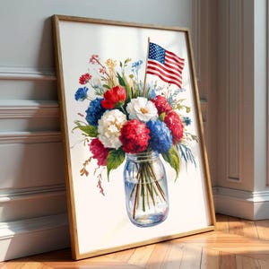 May include: Watercolor print of a bouquet of flowers in a mason jar, featuring red, white, and blue blooms, with an American flag. The artwork is framed in a wooden frame and leans against a white wall.