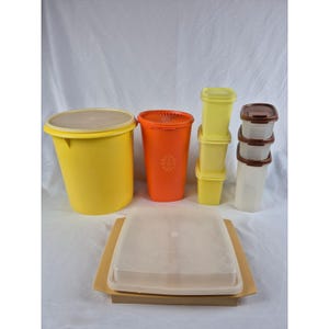 May include: A collection of plastic food storage containers including a large yellow round canister, a tall orange cylindrical container with a floral pattern, three stacked yellow square containers, three stacked translucent containers with brown lids, and a flat tray.