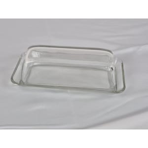 May include: A clear glass butter dish with a rectangular base and a curved, rectangular lid. The dish is made of transparent glass, allowing the contents to be visible. The design is simple and functional, suitable for kitchen use.
