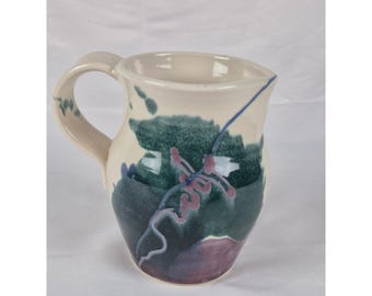 Jarra de cerámica de estudio pintada a mano con diseño abstracto floral, color crema, verde y morado.