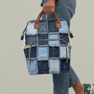 May include: A patchwork denim backpack with brown leather handles. The bag features a variety of blue denim squares, some with polka dots or stripes. The bag has a metal frame and side pockets.
