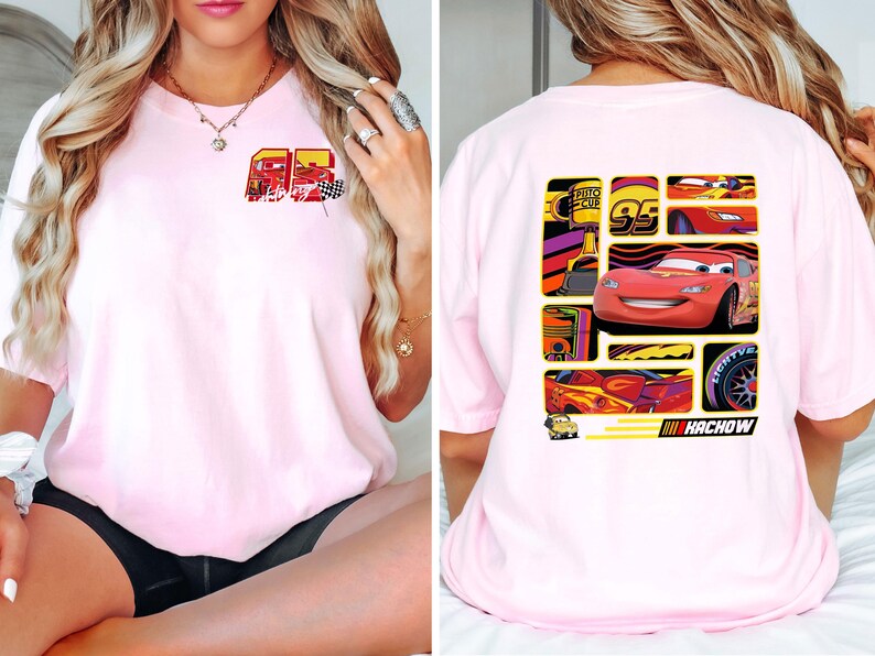 May include: Light pink t-shirt featuring a graphic of a red race car and the number 95. The front of the shirt has a smaller graphic with the number 95 and a checkered flag. The back of the shirt has a larger graphic with the race car and the word "Kachow".