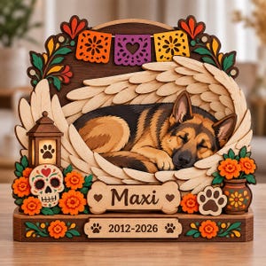 May include: A multi-layered wooden memorial plaque featuring a sleeping German Shepherd dog surrounded by carved angel wings. The design includes a lit lantern, a sugar skull, orange marigold flowers, and a bone-shaped nameplate reading Maxi.