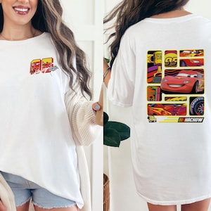 May include: White t-shirt featuring a colorful graphic of a race car and the number 95 on the front. The back of the shirt displays a collage of race car images and the word "Kachow". A fun, casual tee for fans of animated car racing.