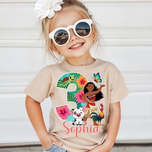 Peut inclure: T-shirt beige &agrave; manches courtes avec un motif color&eacute; du chiffre 3 sur le th&egrave;me tropical, comprenant une tortue, des fleurs et un personnage de dessin anim&eacute;. Le nom "Sophia" est &eacute;crit en rose en dessous.