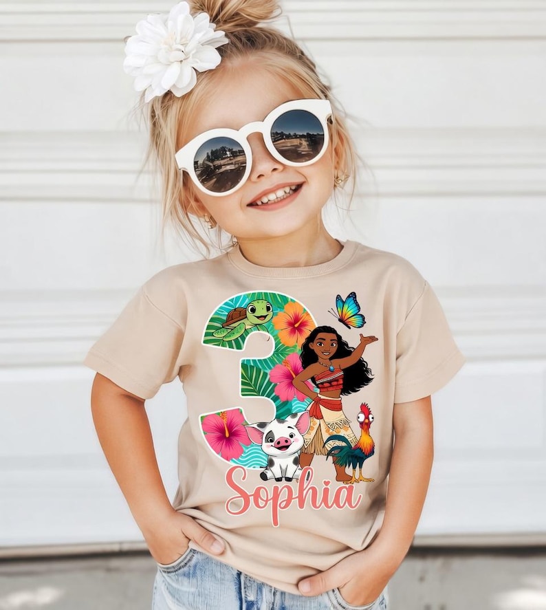 Peut inclure: T-shirt beige &agrave; manches courtes avec un motif color&eacute; du chiffre 3 sur le th&egrave;me tropical, comprenant une tortue, des fleurs et un personnage de dessin anim&eacute;. Le nom "Sophia" est &eacute;crit en rose en dessous.