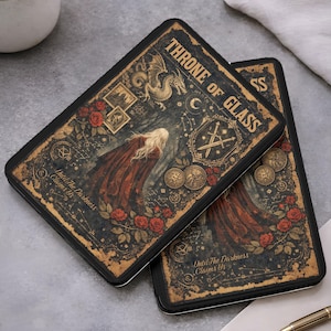 May include: Two rectangular black metal tins featuring a fantasy illustration with the text Throne of Glass and Until The Darkness Claims Us. The design includes a blonde figure in a red cloak, a dragon, swords, roses, and gold celestial motifs.