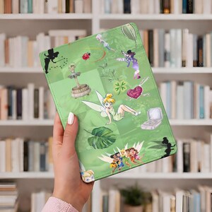May include: A green tablet case featuring illustrations of Tinkerbell and other fairies. The case has a light green background with various images of fairies, a ladybug, and a four-leaf clover. The case is held by a person.