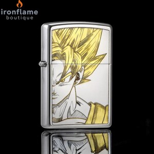 May include: A silver metal lighter featuring a detailed illustration of a character with spiky golden hair. The character's face and upper body are depicted in a stylized, engraved design. The lighter has a rectangular shape and a hinged lid.