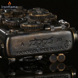 Peut inclure: Gros plan d'un briquet Zippo avec un design steampunk. Le briquet est en bronze fonc&eacute; avec des engrenages visibles et le texte "Zippo 20 BRADFORD PA. MADE IN U.S.A."