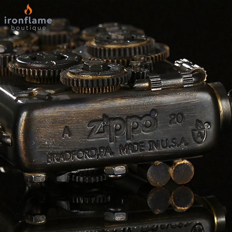 Peut inclure: Gros plan d'un briquet Zippo avec un design steampunk. Le briquet est en bronze fonc&eacute; avec des engrenages visibles et le texte "Zippo 20 BRADFORD PA. MADE IN U.S.A."