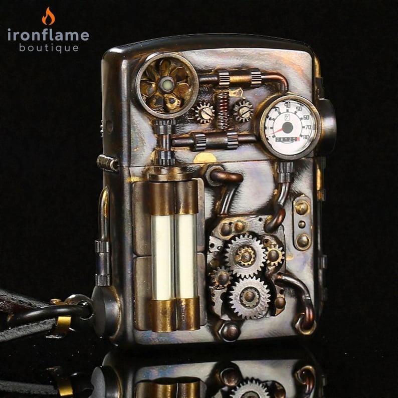 Peut inclure: Briquet de style steampunk avec des engrenages, jauges et tuyaux complexes en tons bronze et argent. Le briquet a un design rectangulaire avec une esth&eacute;tique m&eacute;canique d&eacute;taill&eacute;e, et la marque "ironflame boutique" est visible.