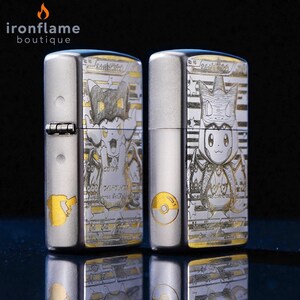 May include: Two silver-colored lighters with detailed engraved designs. One lighter features a cartoon character with a cat-like appearance, while the other showcases a different character. The lighters have gold accents and Japanese text.