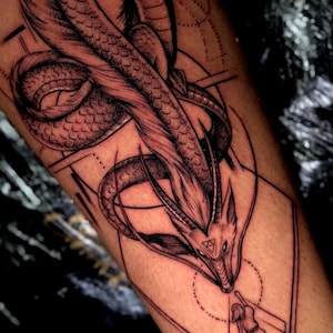 May include: Black and white tattoo featuring a dragon design with geometric elements and a person. The dragon has detailed scales and a feathery mane. The person is within a geometric shape, reaching towards the dragon.