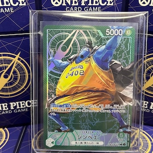 May include: A One Piece card featuring Jinbe in a Lakers jersey. The card has a green background with Japanese text and a 5000 attack power indicator. The card is encased in a protective sleeve.