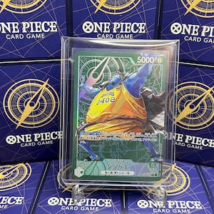 May include: A One Piece card featuring a blue-skinned character in a yellow and orange basketball jersey with the number 0402. The card is in a protective sleeve, with a green and white design. The background shows other One Piece card game cards.