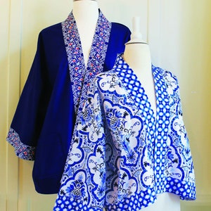May include: Two blue and white patterned jackets with a kimono style. The jacket on the left is a solid blue with a white and red patterned trim. The jacket on the right has a white background with a blue and white floral pattern.