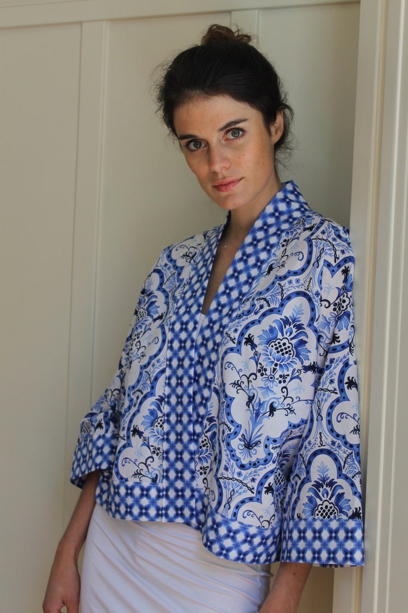 May include: A blue and white patterned kimono-style jacket with a V-neck and 3/4 sleeves.