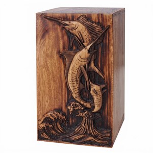 A wooden urn box carved with two leaping marlin fish over stylized ocean waves against a white background.