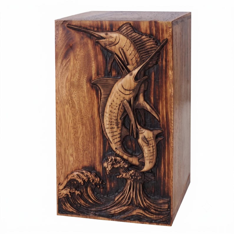 A wooden urn box carved with two leaping marlin fish over stylized ocean waves against a white background.