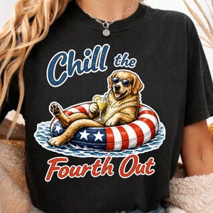 May include: A black t-shirt featuring a graphic of a golden retriever wearing sunglasses, lounging in a red, white, and blue striped pool float while holding a cocktail. The text reads Chill the Fourth Out in blue and red lettering.