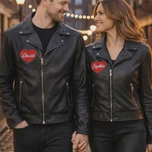 May include: Matching black leather jackets with personalized heart patches. One jacket has "David" embroidered on a red heart, the other "Sophia". Both jackets have a classic biker style with zippers and a sleek, modern look.