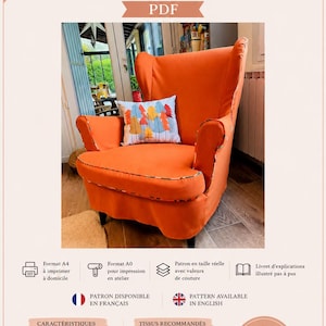 Può includere: Un cartamodello PDF per una fodera per poltrona IKEA Strandmon. L'immagine mostra una poltrona arancione con una fodera coordinata e un piccolo cuscino bianco con una stampa grafica di alberi colorati.
