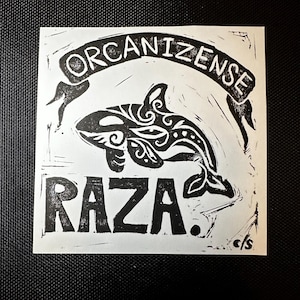 May include: A black and white print featuring an orca with decorative patterns. The word "Organizense" arches above the orca, and the word "Raza" is below. The print has a handmade, linocut style.