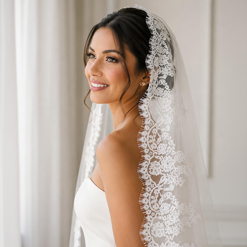 Puede incluir: Un velo de novia blanco y transparente con un intrincado borde de encaje floral. El delicado patr&oacute;n de encaje presenta bordes festoneados y bordados detallados, que caen suavemente sobre la cabeza y los hombros como un accesorio de boda cl&aacute;sico.